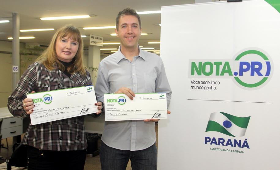 O psicólogo curitibano Marcio Simioni recebeu nesta quarta-feira (18) um cheque simbólico do primeiro prêmio mensal da campanha Nota Fiscal Paranaense, no valor de R$ 30 mil. Ele foi contemplado no sorteio realizado no dia 28 de maio. Outra premiada foi a professora Rosane Bihre Mattes, da rede municipal de ensino de Curitiba, que recebeu um cheque simbólico de R$ 20 mil, referente a um prêmio semanal acumulado.