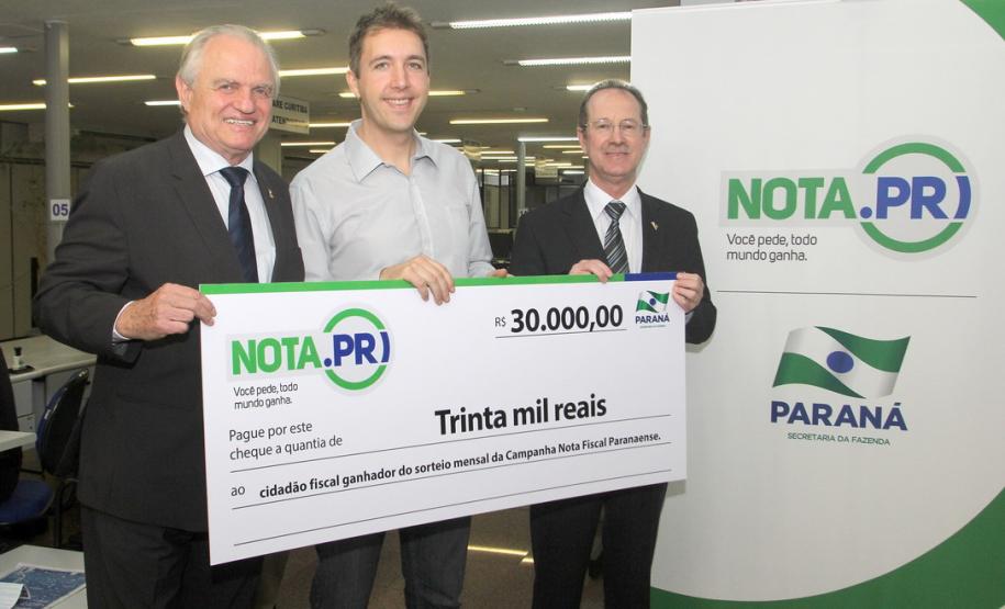 O psicólogo curitibano Marcio Simioni recebeu nesta quarta-feira (18) um cheque simbólico do primeiro prêmio mensal da campanha Nota Fiscal Paranaense, no valor de R$ 30 mil. Ele foi contemplado no sorteio realizado no dia 28 de maio. Outra premiada foi a professora Rosane Bihre Mattes, da rede municipal de ensino de Curitiba, que recebeu um cheque simbólico de R$ 20 mil, referente a um prêmio semanal acumulado.