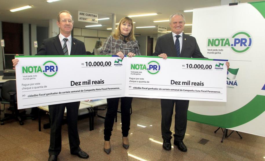 O psicólogo curitibano Marcio Simioni recebeu nesta quarta-feira (18) um cheque simbólico do primeiro prêmio mensal da campanha Nota Fiscal Paranaense, no valor de R$ 30 mil. Ele foi contemplado no sorteio realizado no dia 28 de maio. Outra premiada foi a professora Rosane Bihre Mattes, da rede municipal de ensino de Curitiba, que recebeu um cheque simbólico de R$ 20 mil, referente a um prêmio semanal acumulado.