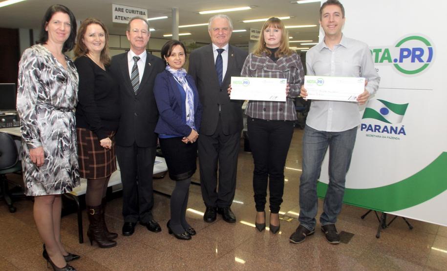 O psicólogo curitibano Marcio Simioni recebeu nesta quarta-feira (18) um cheque simbólico do primeiro prêmio mensal da campanha Nota Fiscal Paranaense, no valor de R$ 30 mil. Ele foi contemplado no sorteio realizado no dia 28 de maio. Outra premiada foi a professora Rosane Bihre Mattes, da rede municipal de ensino de Curitiba, que recebeu um cheque simbólico de R$ 20 mil, referente a um prêmio semanal acumulado.