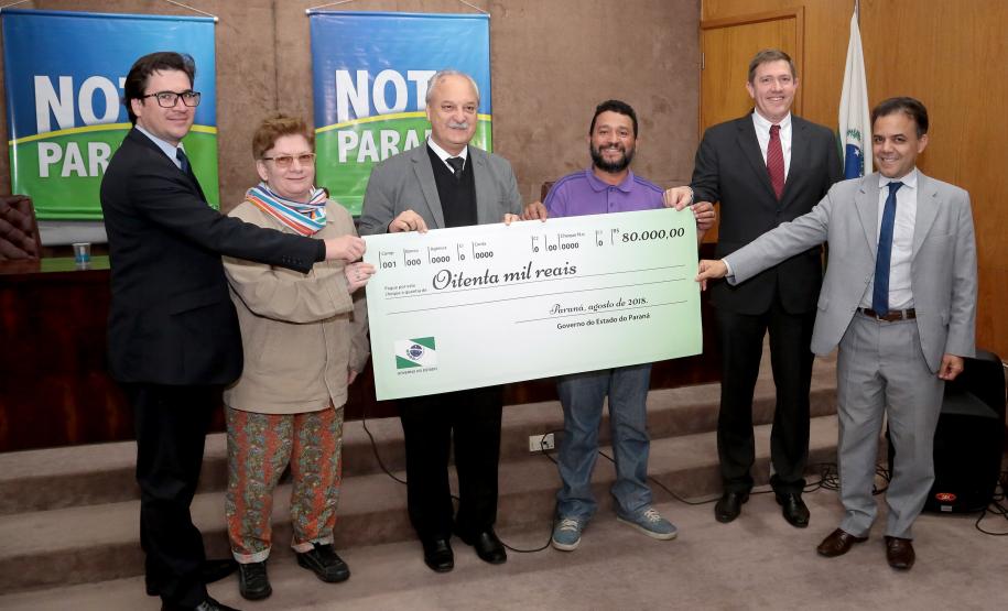 Nota Paraná completa três anos premiando moradores de Curitiba e RMC Os ganhadores dos prêmios de R$ 200 mil, R$ 120 mil e R$ 80 mil recebem os cheques na 33ª premiação do programa Nota Paraná, que neste mês de agosto completa três anos de criação. Por ser o sorteio especial dos pais, o valor das premiações foi multiplicado por quatro. Curitiba,16/08/2018 Foto:Jaelson Lucas / ANPr