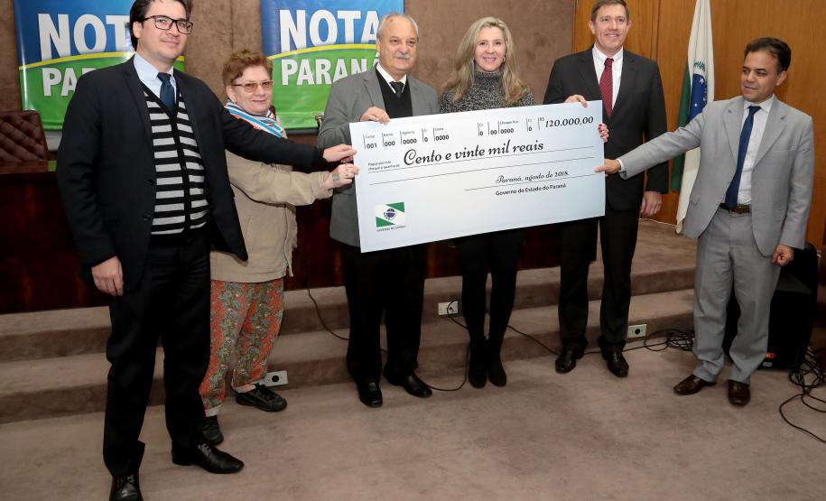 Nota Paraná completa três anos premiando moradores de Curitiba e RMC Os ganhadores dos prêmios de R$ 200 mil, R$ 120 mil e R$ 80 mil recebem os cheques na 33ª premiação do programa Nota Paraná, que neste mês de agosto completa três anos de criação. Por ser o sorteio especial dos pais, o valor das premiações foi multiplicado por quatro. Curitiba,16/08/2018 Foto:Jaelson Lucas / ANPr
