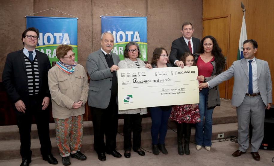 Nota Paraná completa três anos premiando moradores de Curitiba e RMC Os ganhadores dos prêmios de R$ 200 mil, R$ 120 mil e R$ 80 mil recebem os cheques na 33ª premiação do programa Nota Paraná, que neste mês de agosto completa três anos de criação. Por ser o sorteio especial dos pais, o valor das premiações foi multiplicado por quatro. Curitiba,16/08/2018 Foto:Jaelson Lucas / ANPr