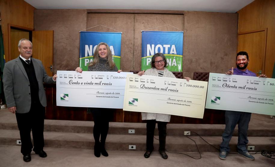 Nota Paraná completa três anos premiando moradores de Curitiba e RMC Os ganhadores dos prêmios de R$ 200 mil, R$ 120 mil e R$ 80 mil recebem os cheques na 33ª premiação do programa Nota Paraná, que neste mês de agosto completa três anos de criação. Por ser o sorteio especial dos pais, o valor das premiações foi multiplicado por quatro. Curitiba,16/08/2018 Foto:Jaelson Lucas / ANPr